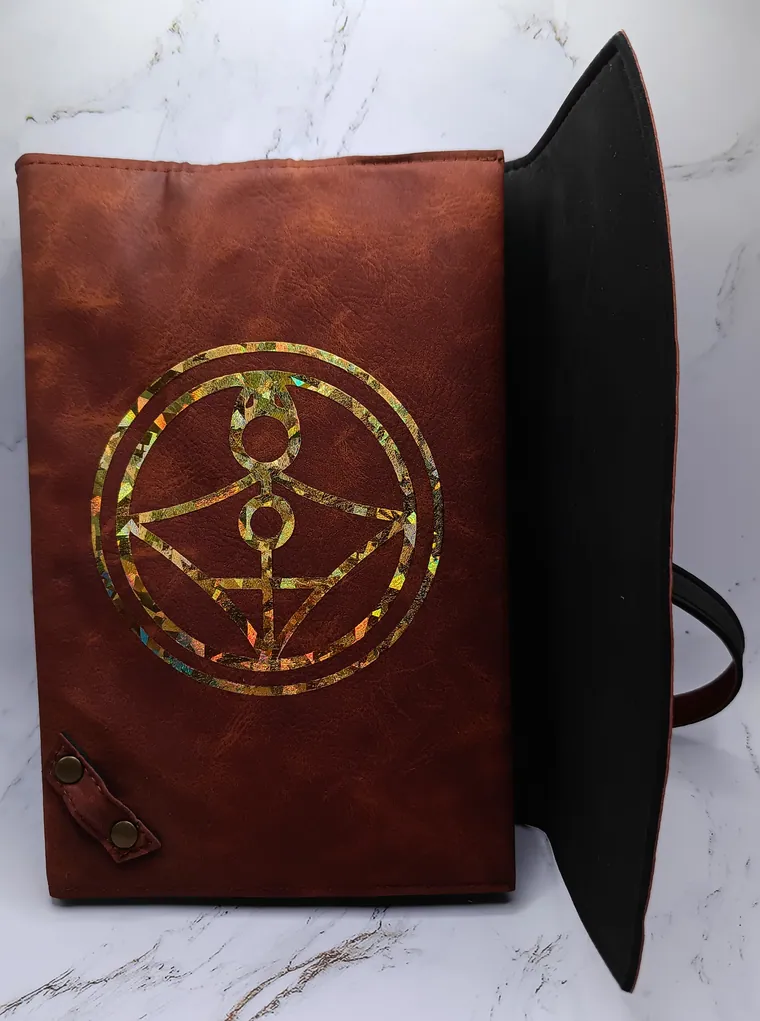 Leather bound grimoire with a gold glyph on the cover.