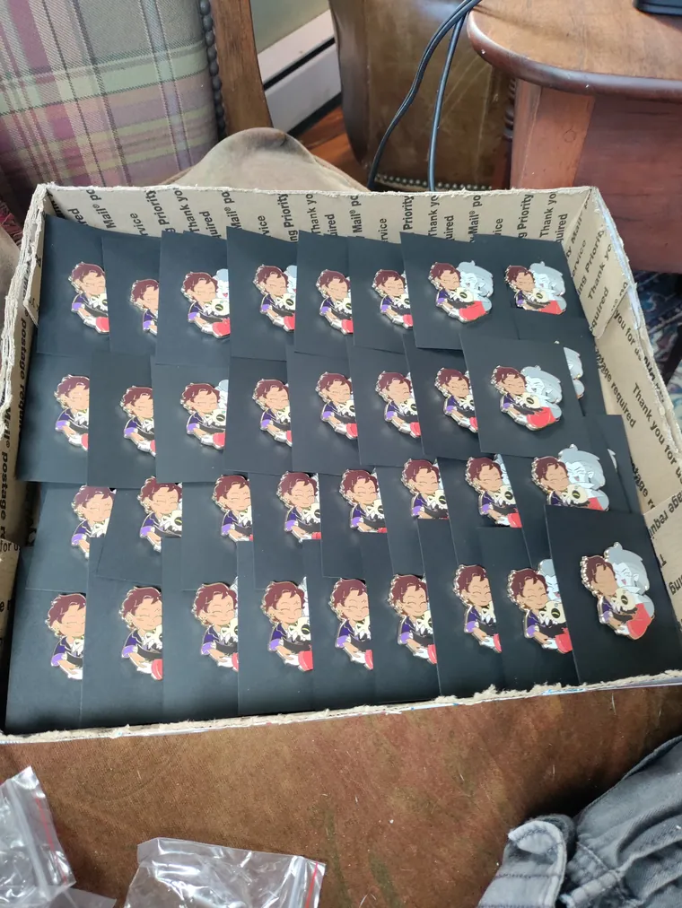 Enamel pins laid out on backing cards before packing.